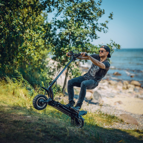 Man riding the Dualtron Ultra 2 electric scooter uphill near the coast, demonstrating power and control on rough terrain.