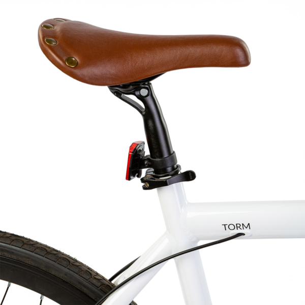 Brown leather saddle of the Oolter Torm white e-bike, including rear light and seat tube detail.