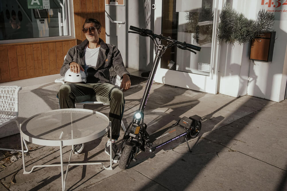 Man relaxing outside with Dualtron Mini Special LB Dual Motor electric scooter parked beside him