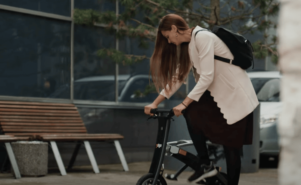 Woman commuting on electric bike Stigo in city wearing business attire