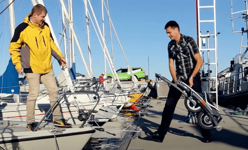 Man carrying folded electric bike Stigo onto a sailboat at marina