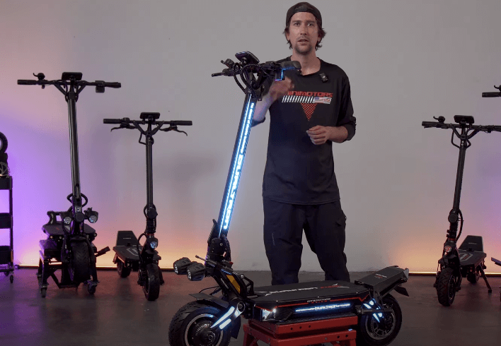 Minimotors presenter showcasing the Dualtron Storm Limited electric scooter with LED lighting during an in-depth breakdown video