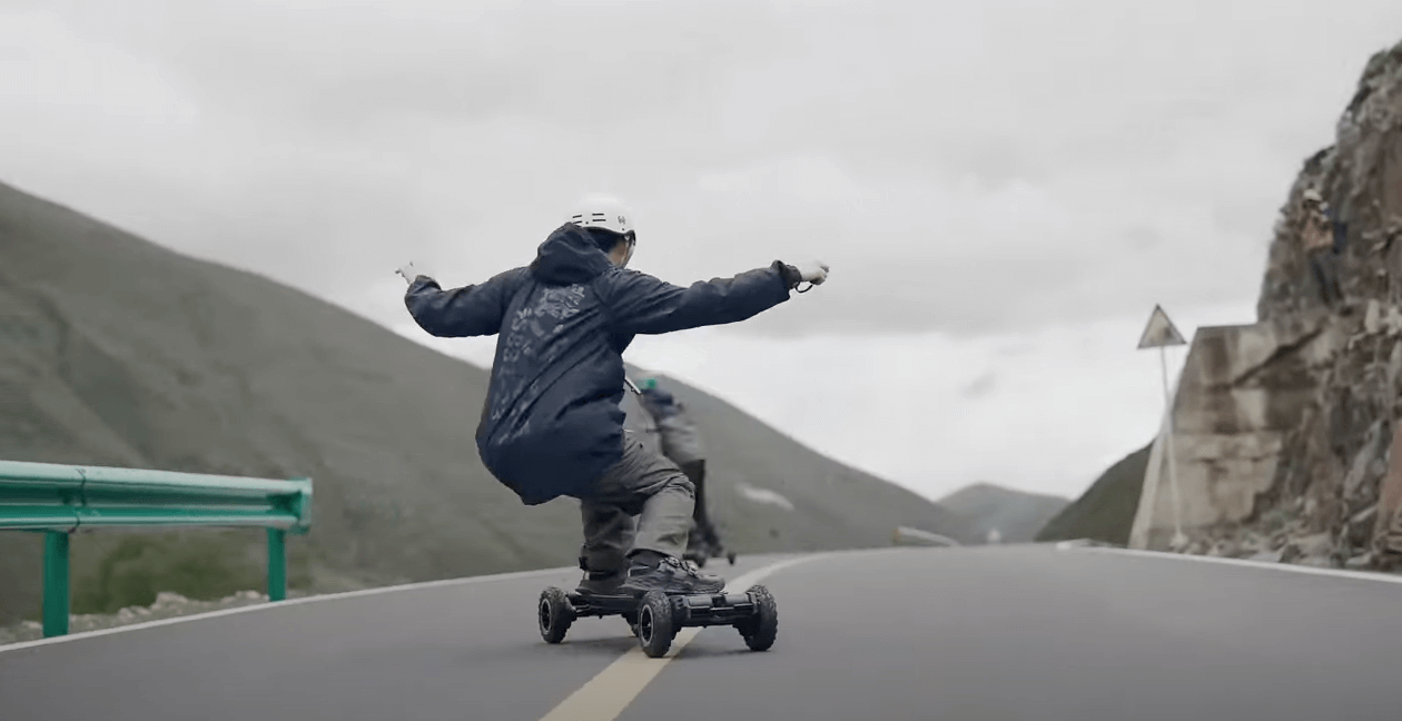 Man riding electric skateboard Exway Atlas Pro 4WD on the highway viewed from the back.