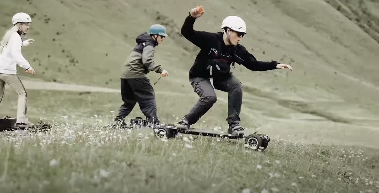 Three people riding Electric skateboards Exway Atlas Pro 2WD on the mountain side.