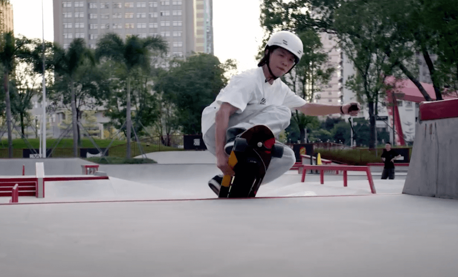 A teenage boy is jumping with Electric skateboard Exway Ripple in the city skatepark wearing a helmet.