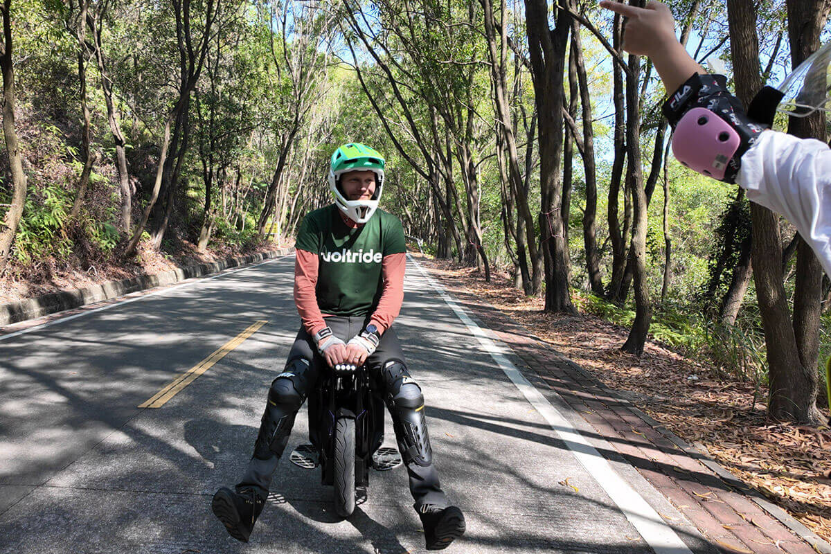 Person sitting on Begode ET Max 50S electric unicycle on a forest road, wearing full safety gear.