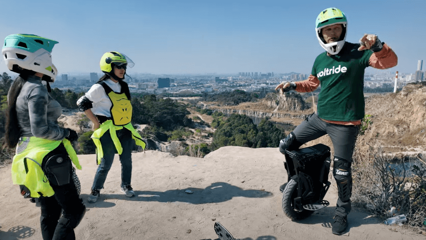Group of riders with Begode ET Max 50S electric unicycle at a scenic overlook, wearing full protective gear.