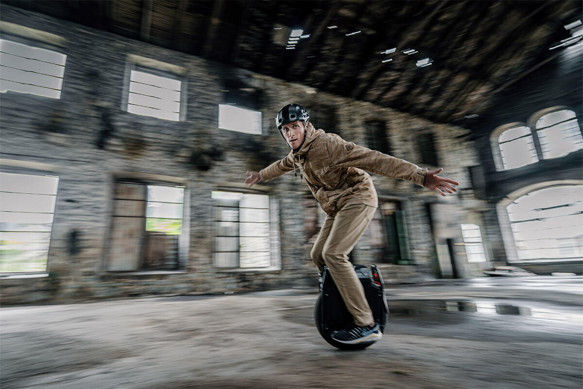 Man riding Veteran Sherman Max electric unicycle at high speed inside an abandoned industrial building, motion blur effect