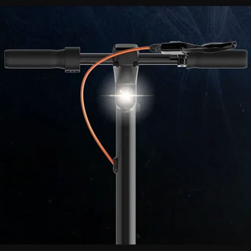 Front view of the Inmotion Climber electric scooter handlebar with a bright headlight turned on, highlighting the scooter’s lighting and control setup against a dark background.