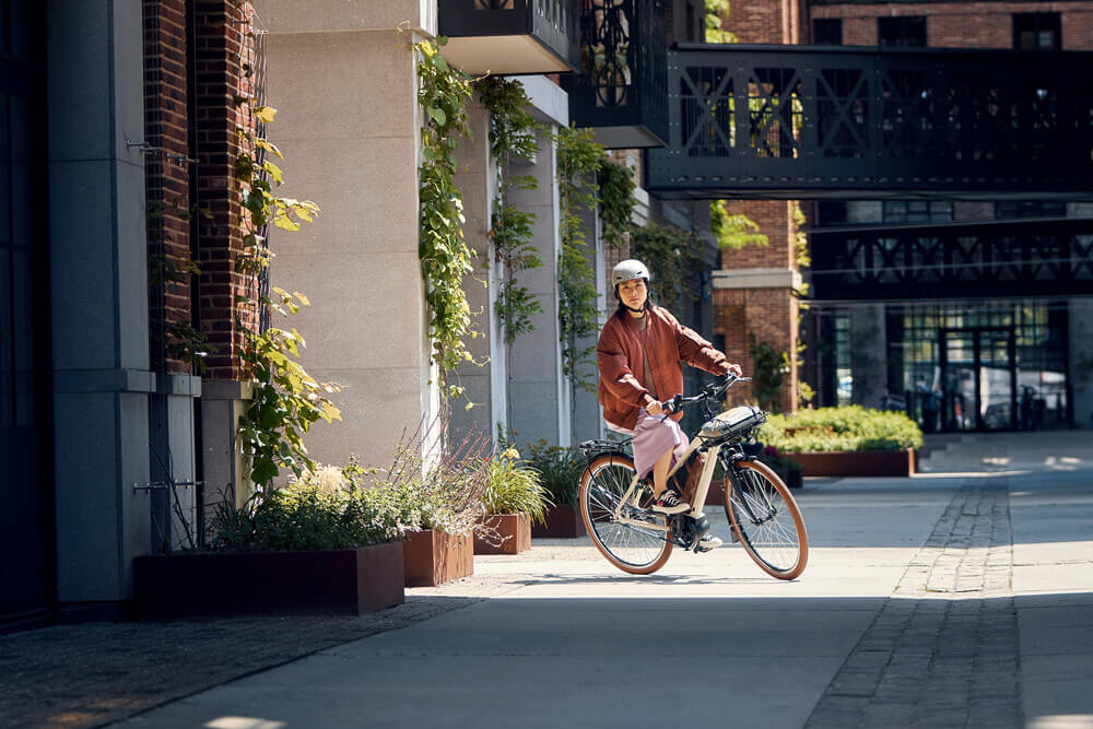 Riese & Müller Cruiser Mixte Silent Lifestyle Image Woman riding the Riese & Müller Cruiser Mixte Silent electric bike in the city