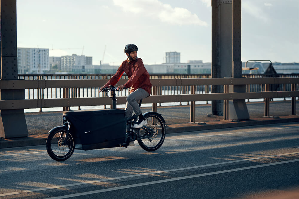 Man riding a Riese & Müller Packster 70 Touring electric cargo bike on a bridge