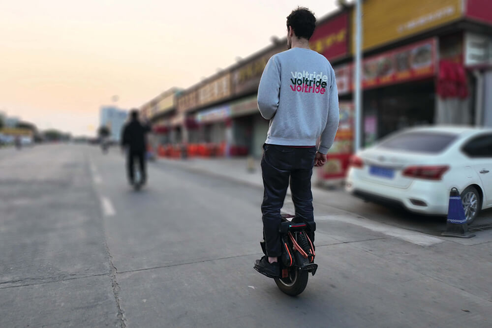 Man riding the Kingsong S16 electric unicycle on a city street.