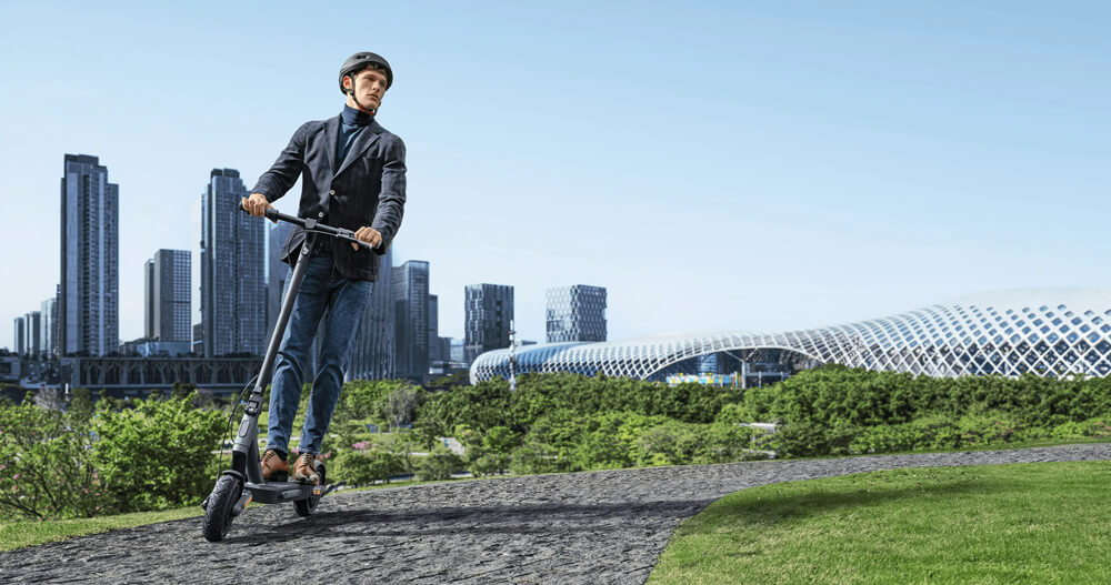 Xiaomi 4 Ultra electric scooter lifestyle Man wearing a helmet and casual business attire riding the Xiaomi 4 Ultra electric scooter on a paved path, with a modern city skyline and futuristic architecture visible in the background.