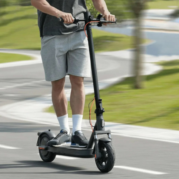 Person riding Xiaomi 5 Elite electric scooter on a city path, showcasing smooth ride and comfortable stance.