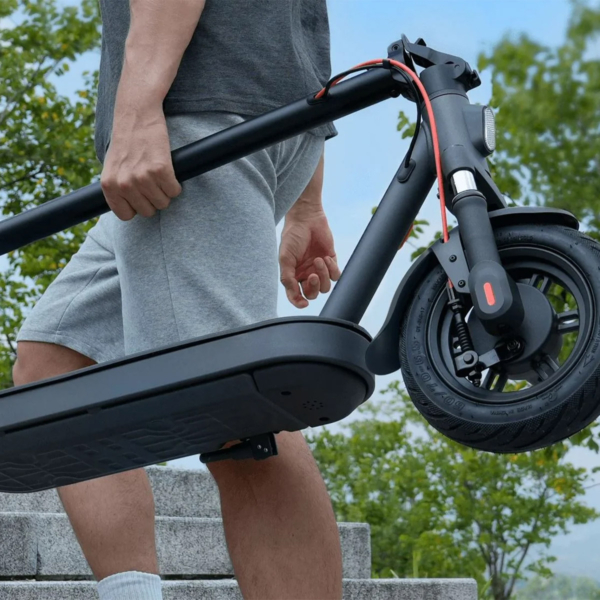 Man carrying folded Xiaomi 5 Elite electric scooter, demonstrating lightweight frame and convenient portability.