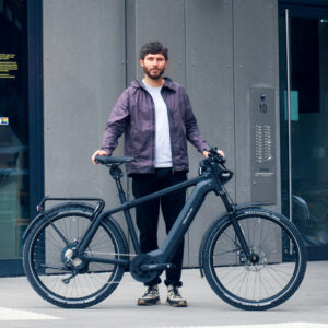 Man standing with a black Riese & Müller Charger4 electric bike, designed for daily commuting and long-distance rides