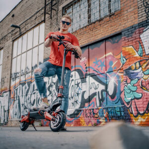 Man posing with GPAD Storm electric scooter in front of colorful graffiti wall