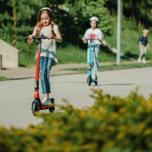 Children riding GPAD Svan electric scooters outdoors with helmets on sunny day