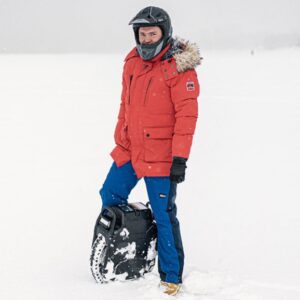 Mies seisoo lumisessa maisemassa Veteran Sherman Max -sähköyksipyörän kanssa, päässään full face -kypärä ja asianmukaiset suojavarusteet