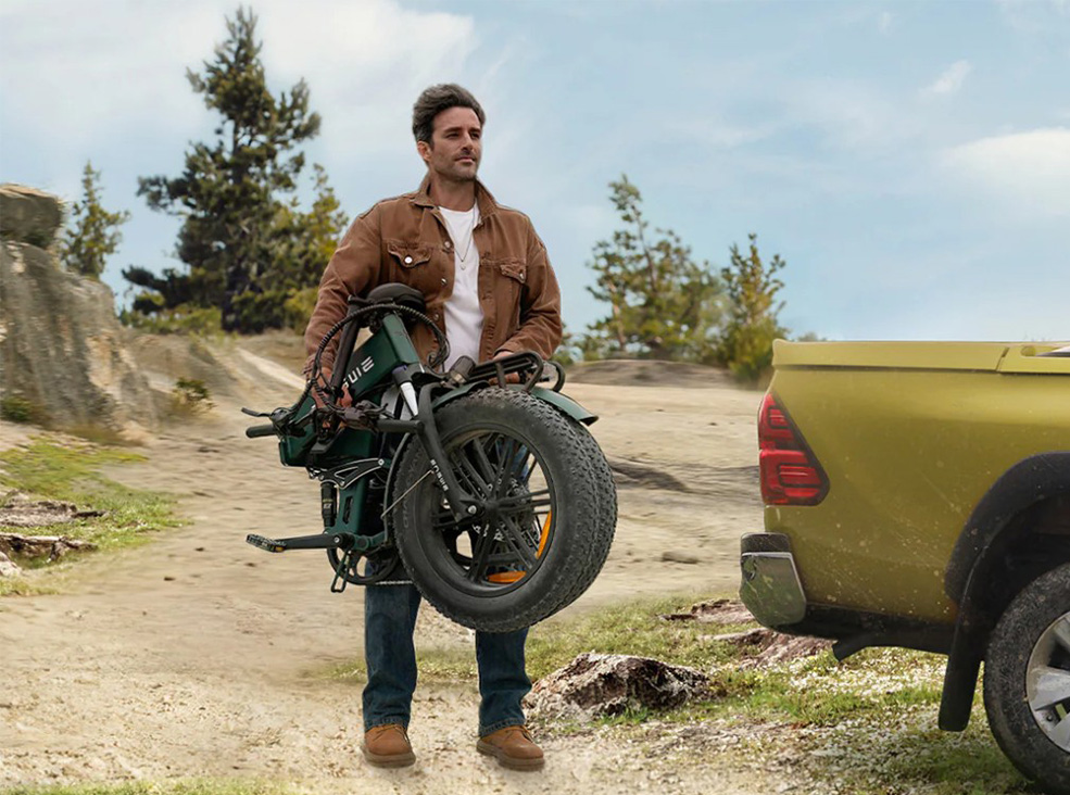 Man carrying the folded Engwe Engine PRO 2.0 electric bicycle demonstrating the bike's foldability.