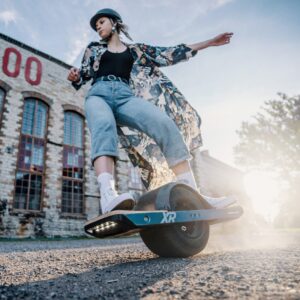 Tyttö ajamassa Onewheel XR Classic -sähköyksipyörällä maastossa kypärä päässä