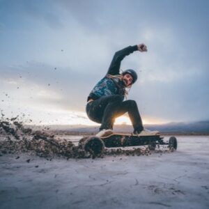 Man riding on offroad with the Evolve Electric Skateboard wearing a helmet.