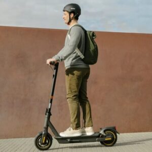 Man riding the Segway MAX G2 electric scooter in the city wearing a helmet.