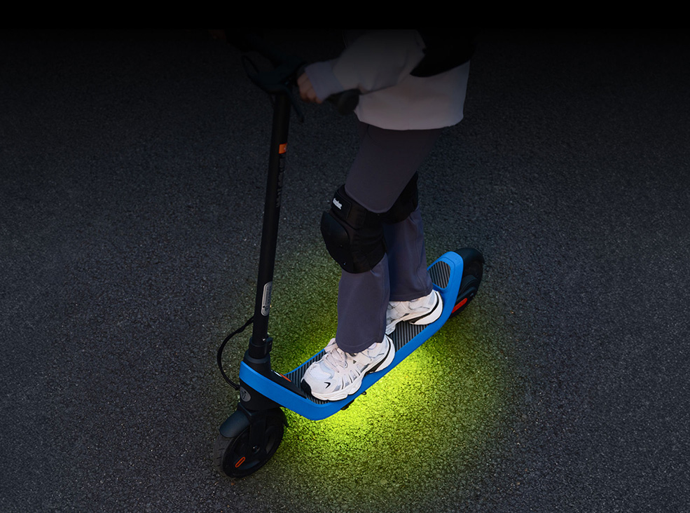 Segway-Ninebot C2 Lite Kids RGB colours Kid standing on the Segway-Ninebot C2 Lite Kids electric scooter with the RGB colors lit.