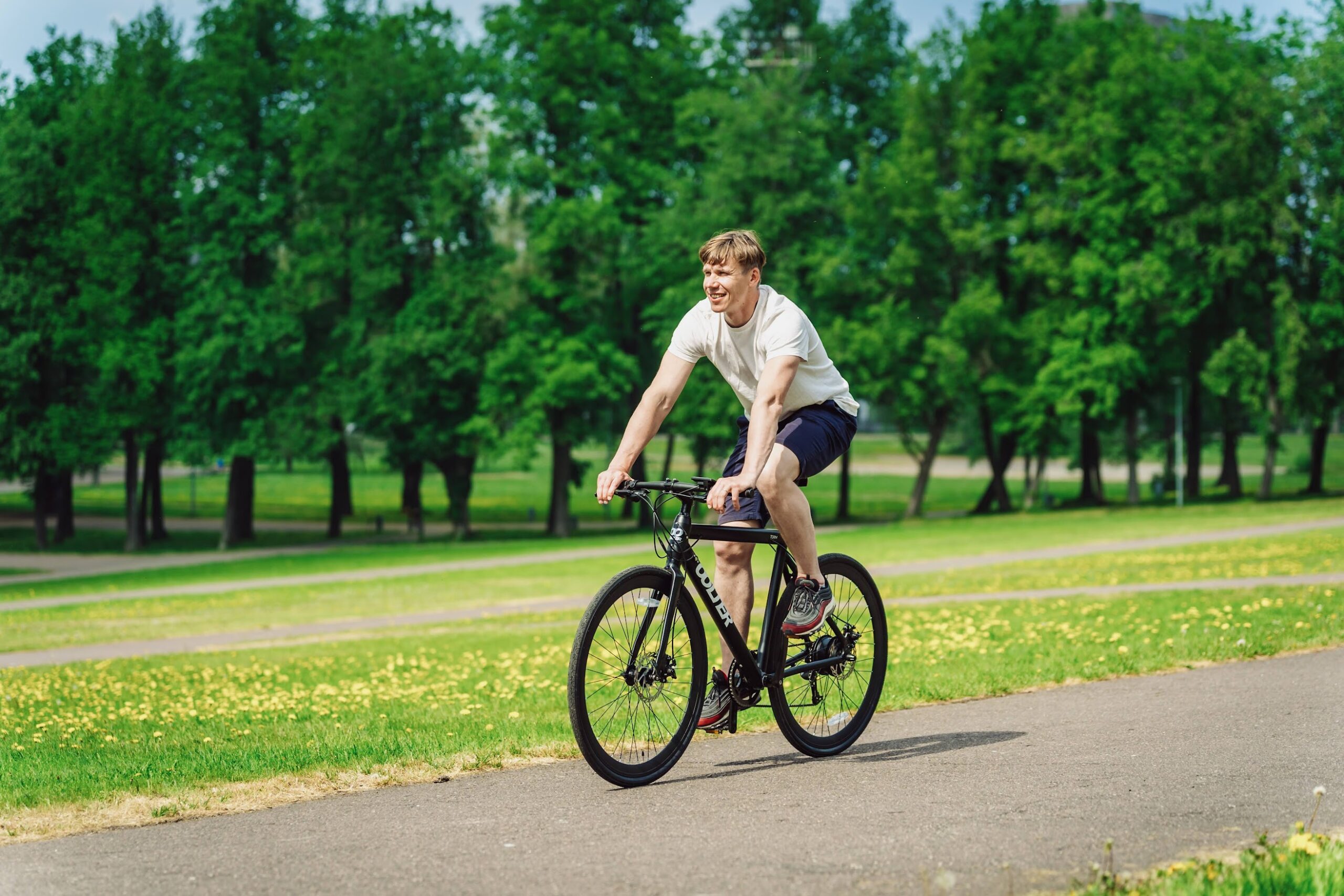 Man riding a city Oolter e-bike on a park road, enjoying urban cycling in nature