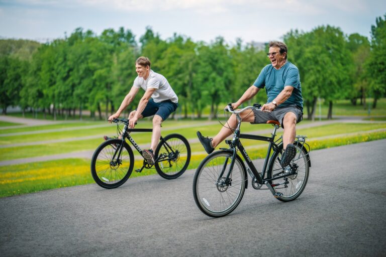 Two men riding Oolter city bikes on a park road, enjoying a comfortable urban cycling experience