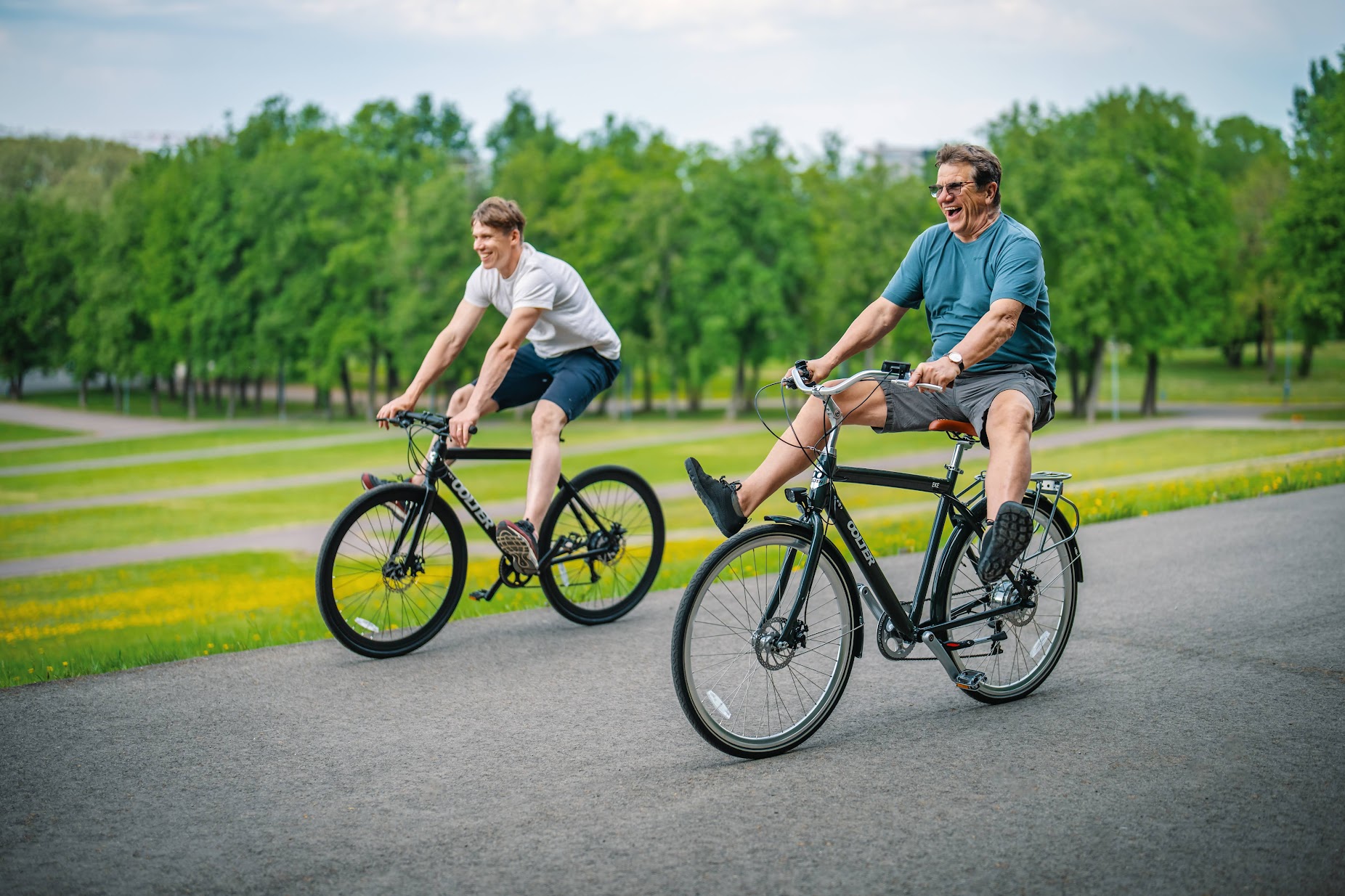 Two men riding Oolter city bikes on a park road, enjoying a comfortable urban cycling experience