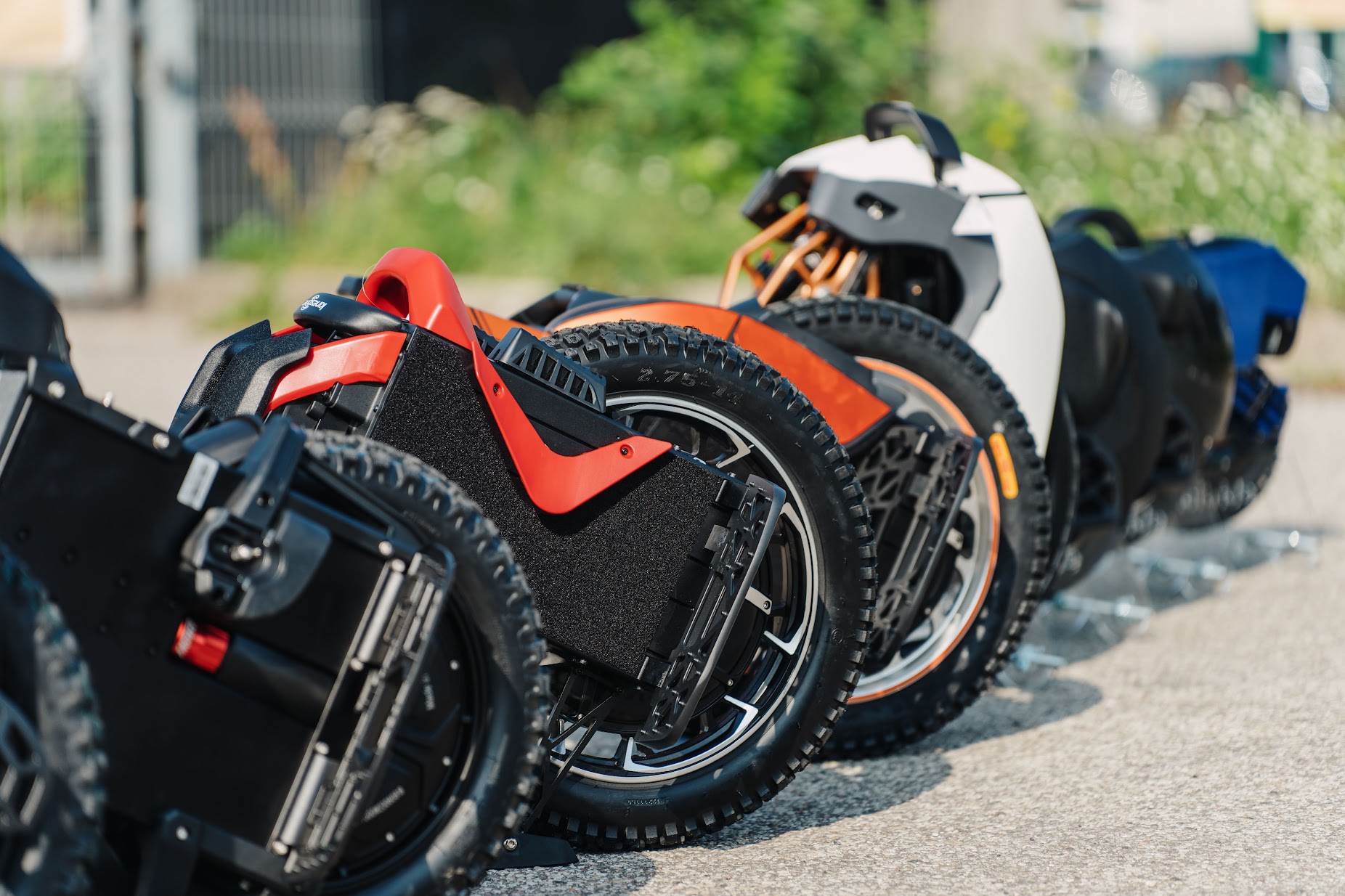 Lineup of electric unicycles parked on a road outdoors