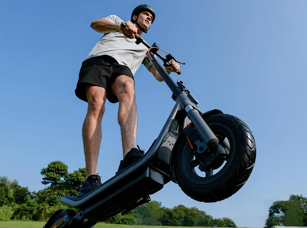Low-angle view of a man riding the Xiaomi 6 electric scooter outdoors while wearing a helmet.