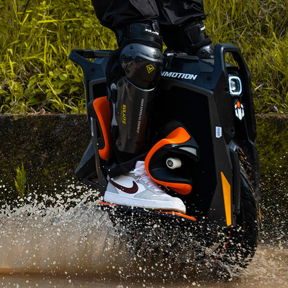 Close-up of a rider crossing through water on an InMotion P6 electric unicycle, showcasing its rugged off-road capability and durable design in wet riding conditions.